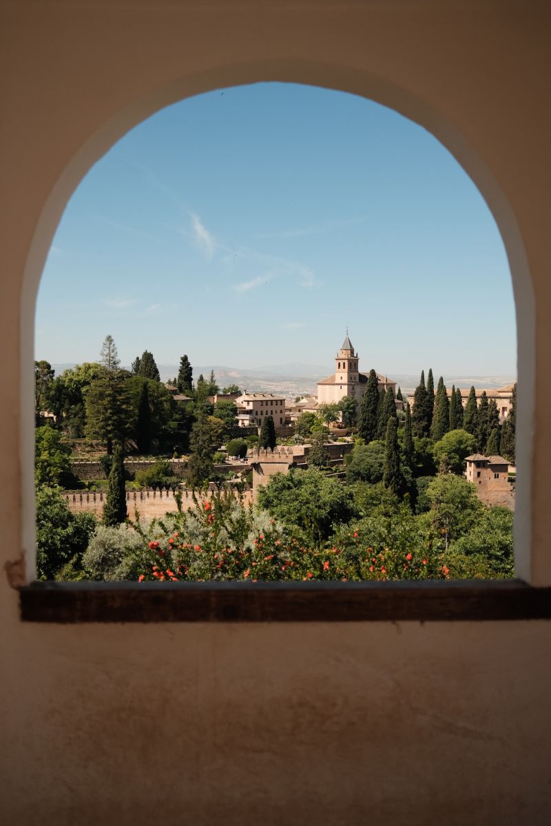 A photo through an window opening showing parts of the Alhambra in Granada, Spain