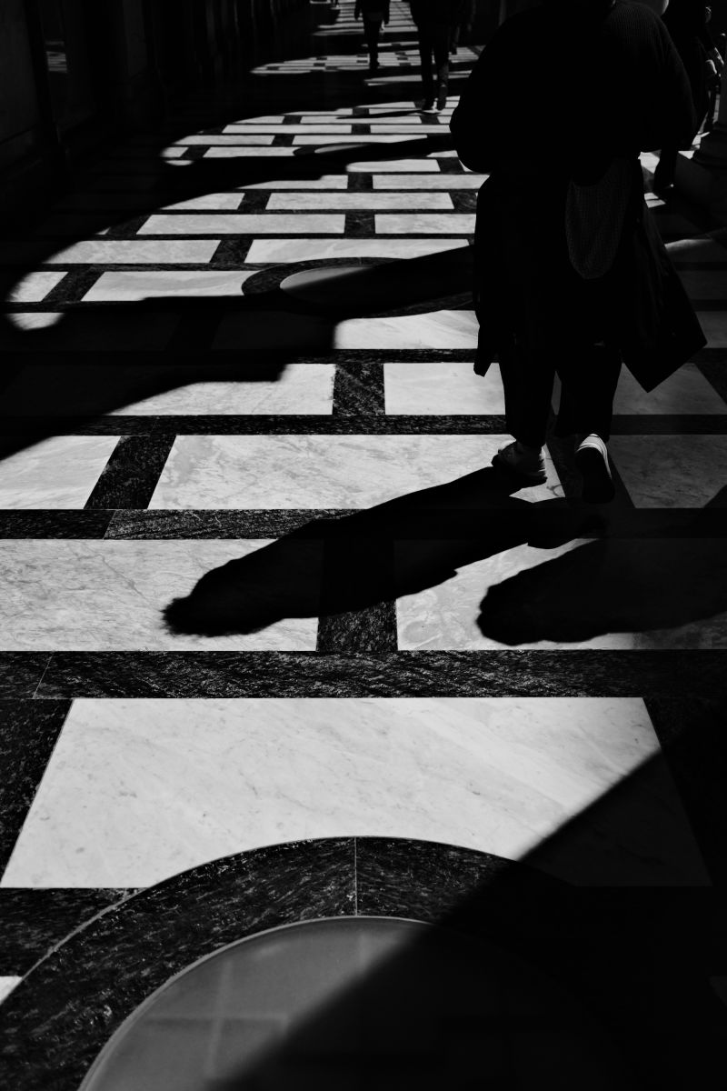 A black and white photo of the floor tiles with shadows of passengers in Milano, Italy