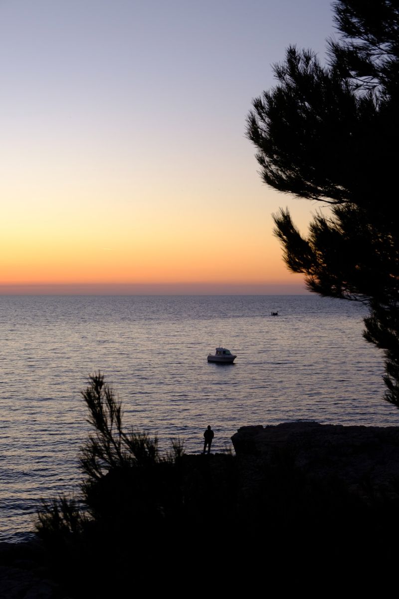 A sunset with a man fishing in Pula, Croatia